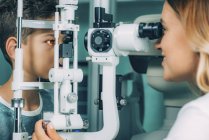 Elementary age boy undergoing sight examination with slit lamp in ophthalmology clinic. — Stock Photo
