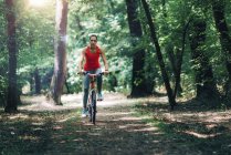 Mid adult woman riding bike in summer park. — Stock Photo