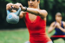 Women exercising outdoors with kettlebell and elastic band. — Stock Photo