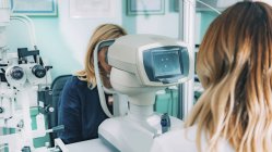 В офтальмологической клинике проводится ауторефрактометрическое обследование глаз пациентки
. — стоковое фото