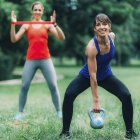 Mujeres haciendo ejercicio al aire libre con pesas y banda elástica . - foto de stock