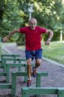 Fit senior man exercising on track with obstacles in park. — Stock Photo