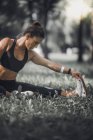 Спортивная женщина растягивает ноги после тренировки в парке . — стоковое фото