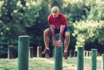 Fitter Senior turnt und springt im Park über Holzpfosten. — Stockfoto