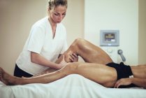 Fisioterapeuta massageando bezerros atleta masculino . — Fotografia de Stock