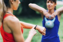 Woman checking progress on smartwatch after outdoor training with friend. — Stock Photo
