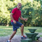 Fit senior man exercising on steps in summer park. — Stock Photo