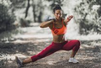 Female athlete doing stretching with kettlebell in park. — Stock Photo