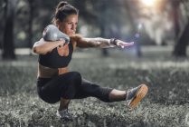 Female athlete exercising with kettlebell in sunny park. — Stock Photo