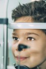 Niño de edad elemental sometido a examen visual con lámpara de hendidura en clínica de oftalmología . - foto de stock