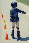Visão traseira do menino praticando rollerskating na classe no parque . — Fotografia de Stock