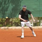 Active senior man playing tennis on court. — Stock Photo