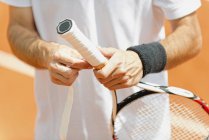 Sezione centrale dell'uomo mettere nuovo nastro grip sulla racchetta da tennis . — Foto stock
