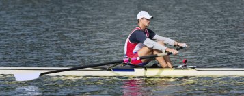 Male athlete rowing single scull rowing boat. — Stock Photo