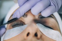Cosmetologist curling eyelashes of patient and using curler in lash lifting procedure. — Stock Photo