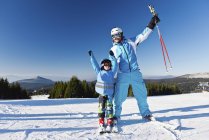 Веселий батько і син позує з лижами на лижному схилі . — стокове фото