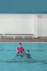 Menino em aula de natação com instrutor em piscina . — Fotografia de Stock