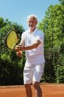 Старший теннисист подает мяч на корте
. — стоковое фото