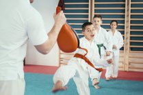 Crianças em idade elementar na aula de taekwondo com treinador . — Fotografia de Stock