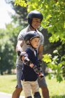 Мальчик учится кататься на роликах с дедушкой в летнем парке . — стоковое фото