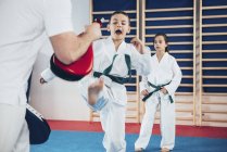 Instructeur de taekwondo formant les enfants en classe . — Photo de stock