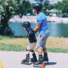 Rapaz aprendendo rollerskating com o avô na estrada com cones . — Fotografia de Stock