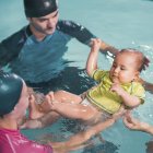 Baby con corso di nuoto con istruttori in piscina . — Foto stock