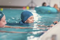 Boy in swimming class with instructor in public pool. — Stock Photo