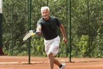 Male senior player practicing tennis on court. — Stock Photo