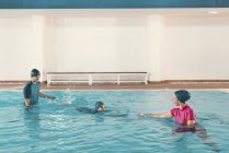 Boy in swimming class with instructors in swimming pool. — Stock Photo