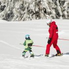 Niño preescolar esquiando con instructor masculino
. - foto de stock