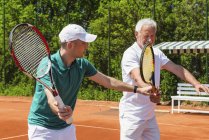 Active senior practicing in tennis class with male instructor. — Stock Photo
