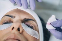 Cosmetologist performing lash lift on female patient in salon. — Stock Photo