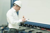 Ingeniero que trabaja en fábrica, tiene lista de verificación y supervisa . - foto de stock