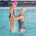 Mujer y niña divirtiéndose en la piscina . - foto de stock