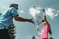 Hombre instructor de tenis entrenamiento adolescente jugador femenino en la cancha . - foto de stock