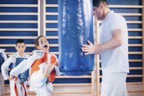 Criança chutando saco de perfuração na classe taekwondo . — Fotografia de Stock