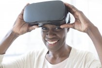 Mulher madura vestindo fone de ouvido realidade virtual e olhando na câmera . — Fotografia de Stock