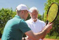 Uomo anziano che fa lezione di tennis con l'istruttore . — Foto stock