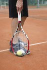 Low section of tennis player picking ball with racket. — Stock Photo