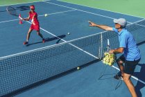 Девочка-подросток на тренировке по теннису на корте с инструктором-мужчиной
. — стоковое фото