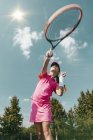 Low angle view of teenager practicing tennis on court. — Stock Photo