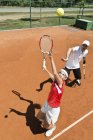 Jogador de tênis adolescente que pratica serviço com instrutor . — Fotografia de Stock