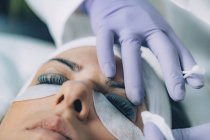 Косметолог наносит черную краску на ресницы пациента во время процедуры поднятия ресниц и ламинирования . — стоковое фото