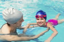 Маленька дівчинка вчиться плавати з інструктором у громадському басейні . — стокове фото