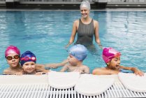 Children in swimming class with female instructor in swimming pool. — Stock Photo