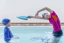 Niño teniendo clase de natación con instructor femenino en la piscina . - foto de stock
