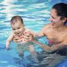 Bébé garçon et mère dans l'eau de la piscine . — Photo de stock