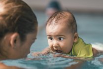 Femme avec fils ayant des cours de natation pour bébé dans la piscine . — Photo de stock