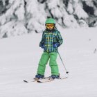 Маленький хлопчик в зимовому одязі лижі на снігових горах. — стокове фото